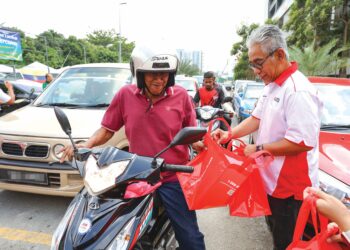 TENGKU Ahmad Badli Shah Raja Hussin (kanan) mengedarkan bubur lambuk kepada orang ramai pada program Kongsi Berkat Bubur Lambuk anjuran Media Mulia bersama Agro Bank di Surau Jumaat Al-Husna Seri Semarak, Kuala Lumpur Khamis lalu.  – UTUSAN/FARIZ RUSADIO