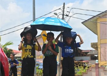 MURID sekolah menutup kepala menggunakan beg dan payung berikutan cuaca panas di pekarangan luar Sekolah Kebangsaan Padang Mengkuang, Marang, baru-baru ini. MINGGUAN/PUQTRA HAIRRY ROSLI