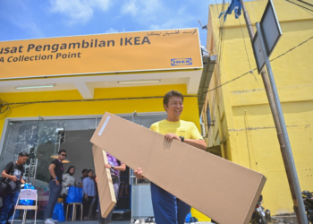 TAKESHI Murai membantu mengangkat barangan milik pelanggan di pusat pengambilan baharu IKEA di Kuala Terengganu, hari ini. - UTUSAN/PUQTRA HAIRRY ROSLI