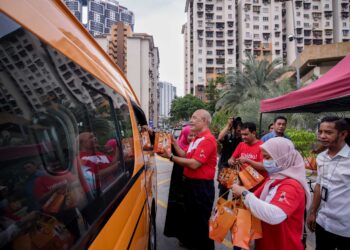 Roslan Mahayudin menyerahkan bubur lambuk sumbangan Mahsuri Dagang kepada orang ramai di sekitar PPR Seri Semarak, Kuala Lumpur, hari ini.