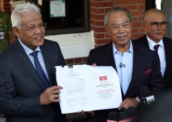 MUHYIDDIN Yassin (kanan) menunjukkan salinan pindaan Perlembagaan Bersatu yang diserahkan kepada RoS, Putrajaya. - UTUSAN/HUSNI MOHD NOOR