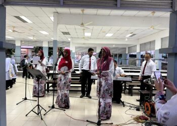 TIGA guru wanita menyanyi untuk menyambut murid-murid pada hari pertama persekolahan di SK Putrajaya Presint 17(1). - UTUSAN/KAMARIAH KHALIDI