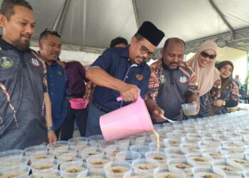 ADNAN Mat menuangkan bubur lambuk dalam bekas makanan pada majlis penyerahan bubur lambuk oleh Gabungan Kesatuan Pekerja-Pekerja Dalam Perkhidmatan Kerani dan Bersekutu Kerajaan (Auegcas) di Ipoh hari ini. - UTUSAN