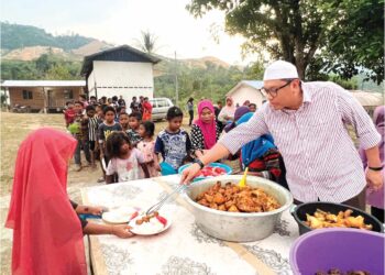 MOHD. Syahbuddin Hashim membantu mengagihkan makanan berbuka puasa kepada masyarakat Orang Asli di Kampung Mendrod, Pos Brooke, Gua Musang, Kelantan. – UTUSAN/AIMUNI TUAN LAH