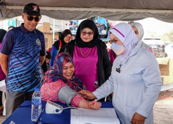 TUMINAH Kadi (tengah) melihat pemeriksaan kesihatan ketika Program Empowering Women sempena sambutan Hari Wanita Sedunia di Pantai Puteri, Melaka. - UTUSAN/SYAFEEQ AHMAD