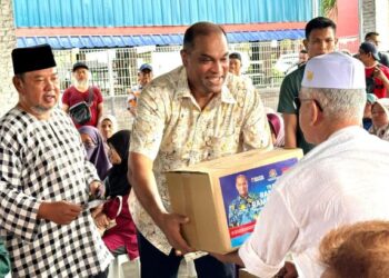 R. RAMANAN menyerahkan bakul makanan kepada salah seorang penerima sambil diiringi oleh Ketua UMNO Bahagian Sungai Buloh, Datuk’ Megat Firdouz (kiri).