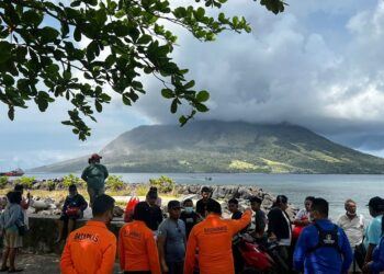GAMBAR edaran Badan Mencari dan Menyelamat Nasional (BASARNAS) Indonesia yang diterima semalam  menunjukkan orang ramai di Sitaro, Sulawesi Utara melihat gunung berapi Gunung Ruang mengeluarkan asap. -AFP