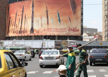 PENGGUNA jalan raya melintasi papan iklan yang memaparkan imej peluru berpandu Iran di Teheran, kelmarin. - AFP