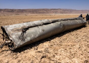 JURUGAMBAR berdiri di hadapan sisa peluru berpandu yang mendarat di pantai Laut Mati, seminggu selepas serangan peluru berpandu yang dilepaskan oleh Iran pada 13 April lalu. -AFP