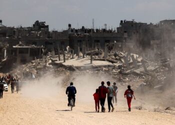 PENDUDUK Palestin menggunakan jalan yang dipenuhi dengan bangunan yang rosak dan musnah di Khan Younis pada 7 April lalu selepas Israel berundur dari selatan Gaza. -AFP