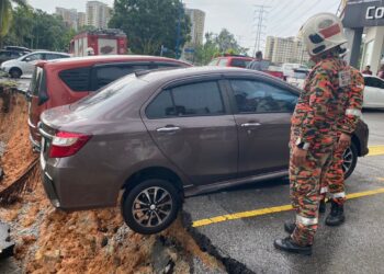 DUA buah kereta hampir terjatuh dari tebing yang runtuh di tempat letak kenderaan.