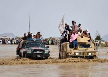 SEKUMPULAN penduduk Afghanistan menaiki kenderaan tentera ketika melintasi kawasan banjir di wilayah Kandahar.-AFP