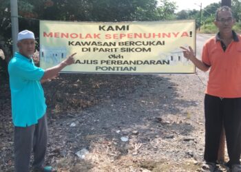 MD. RAZI Md. Jidi (kanan) dan seorang penduduk menunjukkan kain rentang menolak cadangan peluasan kawasan bercukai oleh MPPn bermula 1 Jun depan di Parit Sikom, Pontian.