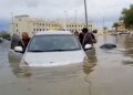BEBERAPA lelaki menolak kereta mereka yang tenggelam akibat banjir di Dubai.-AFP