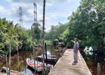 AZMAN Awang menunjukkan laluan keluar dan masuk di Jeti Nelayan Sungai Boh, Pontian yang terpaksa melalui bawah jambatan yang dasarnya cetek ketika air surut.