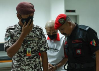 TERTUDUH diiringi anggota Jabatan Penjara semasa menghadiri prosiding di Mahkamah Tinggi, Kota Bharu, Kelantan semalam. -UTUSAN/ROSALWANI CHE SOH.