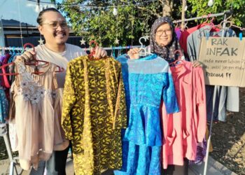 NURUL Husna Radhiah Harun dan suaminya, Nik Bariqi Mohd. Noor Azahar menunjukkan pakaian raya terpakai yang dikumpul di Kota Putera Square, Kampung Raja, Besut. -  UTUSAN/ WAN ZURATIKAH IFFAH WAN ZULKIFLI