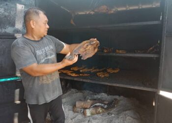 ALI Mat Isa menunjukkan ikan salai patin dan tilapia hasil ternakan sangkar untuk dijual di gerai berdekatan Jalan Jerantut-Maran di Kampung Jerantut Feri di Jerantut, Pahang. – UTUSAN/HARIS FADILAH AHMAD