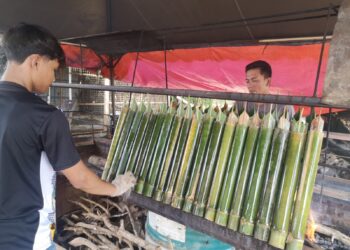 MD Azizi Mohammad (kanan) dibantu anak lelakinya, Muhammad Aidil Ikmal, 19, membakar lemang di Gerai Lemang Daun Lerek Tok Abah di Jalan Jelebu, Ampangan, Seremban.-UTUSAN/NUR SHARIEZA ISMAIL.