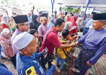 MOHAMAD Hasan bersalaman dengan tetamu dalam majlis rumah terbuka Aidilfitri anjurannya di Kampung Tanjung, Rantau, Seremban semalam. – mingguan/MOHD. SHAHJEHAN MAAMIN