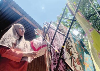 SEORANG suri rumah menjemur pakaian di halaman rumahnya di Gua Musang, Kelantan semalam. – UTUSAN/AIMUNI TUAN LAH