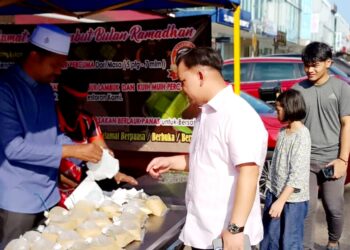 SAHUL Hamed (kiri) memberikan bubur lambuk pada orang ramai di Restoran E&Y Taman Adda Heights Johor Bahru.