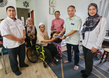 MOHAMAD Mohyddin Mohamed Nor (dua dari kanan) menyampaikan sumbangan kepada Azlan Bahrum di Kuala Terengganu, semalam.