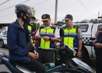 LOKMAN Jamaan (dua dari kanan) memeriksa seorang penunggang motosikal ketika operasi JPJ di Jalan Tun Fatimah, Bachang, Melaka. - UTUSAN/MUHAMMAD SHAHIZAM TAZALI