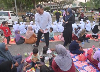 MOHD. SHARIM Md. Zin menyampaikan duit raya kepada kanak-kanak yang hadir pada Majlis Berbuka Puasa Bersama Penduduk Dewan Undangan Negeri (DUN) Chini di Dataran Chini di Pekan, Pahang. - FOTO/SHAIKH AHMAD RAZIF