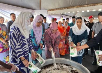TUNKU Azizah Aminah Maimunah Iskandariah (tiga dari kiri) memasukkan santan ketika proses menyediakan bubur lambuk resipi Istana Pahang di Penjara Marang, Terengganu, semalam. - UTUSAN/KAMALIZA KAMARUDDIN