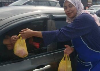 NOR Fatirah Abdullah mengagihkan minuman kepada orang ramai yang terlibat dalam kesesakan lalu lintas di Kampung Chalok, Setiu, hari ini. - UTUSAN/WAN ZURATIKAH IFFAH WAN ZULKIFLI