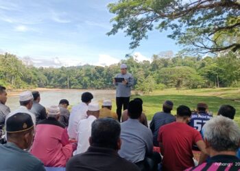 SEBAHAGIAN penduduk mendengar khutbah disampaikan Izzuddin Abd. Mutalib (berdiri)  selepas solat sunat istisqa di lapangan pinggir Sungai Tembeling, Ulu Tembeling di Jerantut, Pahang. - FOTO/HARIS FADILAH AHMAD