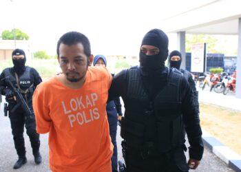 HAFIZUL Hawari diringi oleh 
anggota polis dari Unit D9 (Bahagian Siasatan Jenayah Berat) lengkap bersenjata semasa hadir untuk permohonan sambungan reman du Mahkamah Majistret Kota Bharu, Kelantan-UTUSAN/KAMARUL BISMI KAMARUZAMAN.