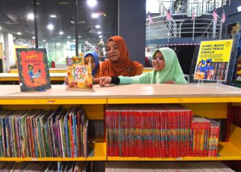 JAMILAH Katis (tengah) menyantuni pelajar sekolah yang sedang mencari bahan bacaan di PPANS di Seremban 2, Seremban baru-baru ini.-UTUSAN/NUR SHARIEZA ISMAIL.