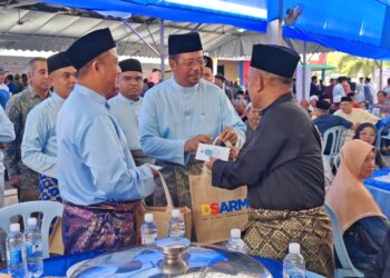 ABDUL RAHMAN Mohamad (tengah) menyampaikan sumbangan kepada salah seorang bakal jemaah haji sempena majlis jamuan Hari Raya Aidilfitri peringkat Kementerian Sumber Manusia di Lipis, Pahang. - UTUSAN/HARIS FADILAH AHMAD