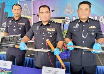 BAHRIN MOHD. NOH (tengah) menunjukkan pedang yang digunakan oleh empat lelaki menyamun kedai serbaneka di Taman Intan, Kluang pada 19 April lalu.