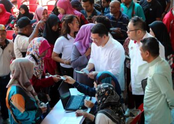 NGA Kor Ming menyerahkan sumbangan baucar Hari Raya Aidilfitri kepada penerima pada Program Meriah Beraya di Angsana Mall di Ipoh hari ini. - UTUSAN