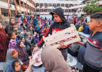 SEORANG remaja lelaki Palestin mengagihkan makanan kepada yang lain dalam suasana Hari Raya Aidilfitri yang disambut secara sederhana.