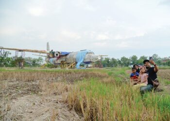 ORANG ramai mengambil kesempatan bergambar berlatar belakangkan kapal terbang lama di tengah bendang di Kampung Panggau, Tok Kuning, Perlis.– MINGGUAN/IZLIZAN OTHMAN