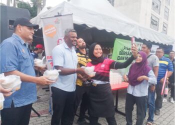J. ARUL Kumar diiringi Hazahar (kiri) mengagihkan bungkusan lemang dan rendang kepada orang ramai pada Program Ihya Ramadan Bersama Jabatan, Agensi dan Masyarakat Setempat di Bazar Ramadan Bandar Baru Nilai di Seremban. – UTUSAN/NUR SHARIEZA ISMAIL