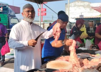 SYED Abu Hussin Hafiz Syed Abdul Fasal melapah daging pada  jualan murah sempena Aidilfitri di Bukit Gantang hari ini. - UTUSAN/WAT KAMAL ABAS