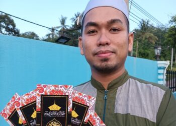 MUHAMMAD Fazrin Mahamad Nazeri menunjukkan sampul raya keluaran Masjid An-Nuhiah di Kampung Ribu dekat Kuala Kangsar. - UTUSAN