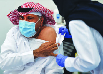 This picture taken on December 17, 2020 shows the first Saudi citizen preparing to receive the Pfizer-BioNTech COVID-19 coronavirus vaccine (Tozinameran) in the capital Riyadh, as part of a vaccination campaign by the Saudi health ministry. (Photo by FAYEZ NURELDINE / AFP)