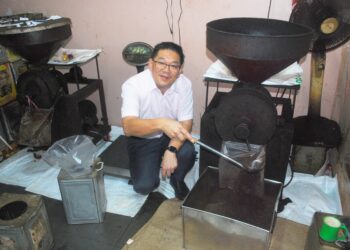 LIM Ban Hong menunjukkan biji kopi yang diproses di sebuah kilang di Pulau Gadong, Klebang, Melaka. - UTUSAN/AMRAN MULUP