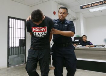 TERTUDUH diiringi polis semasa menghadiri prosiding di Mahkamah Sesyen Kota Bharu, Kelantan hari ini-UTUSAN/ROSALWANI CHE SOH