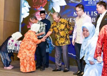 ANIFAH Aman (tengah) bersalaman dengan penerima sumbangan pada majlis berbuka puasa Invest Sabah Berhad di Kota Kinabalu semalam.