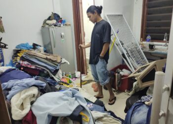 MUHAMMAD Yusri Johari melihat pakaian jualannya yang terjejas ekoran kejadian banjir kilat yang melanda pekan Kota, Rembau hari ini-UTUSAN/NOR AINNA HAMZAH.