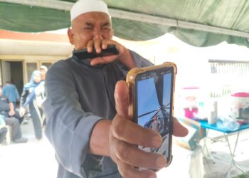 RAMLI Abd. Hamid tidak dapat menahan sebak ketika menunjukkan gambar anak sulungnya yang terkorban dalam nahas dua helikopter di Pangkalan Tentera Laut Diraja Malaysia (TLDM) Lumut, Perak awal pagi semalam.-UTUSAN/SAFINA RAMLI