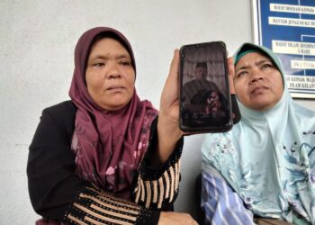 JUHASNI Naini Junoh (kiri) menunjukkan gambar adiknya, Juhazrie Junoh yang maut dalam kemalangan ketika ditemui di perkarangan Unit Forensik Hospital Sultan Ismail Petra, Kuala Krai, Kelantan. UTUSAN/ROSMIZAN RESDI