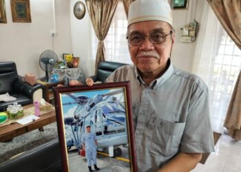 MOHD. Termizi Abdul Ghani menunjukkan gambar anaknya, Mohd. Shahrizan Mohd. Termizi yang maut dalam kejadian helikopter TLDM terhempas di Lumut. - UTUSAN